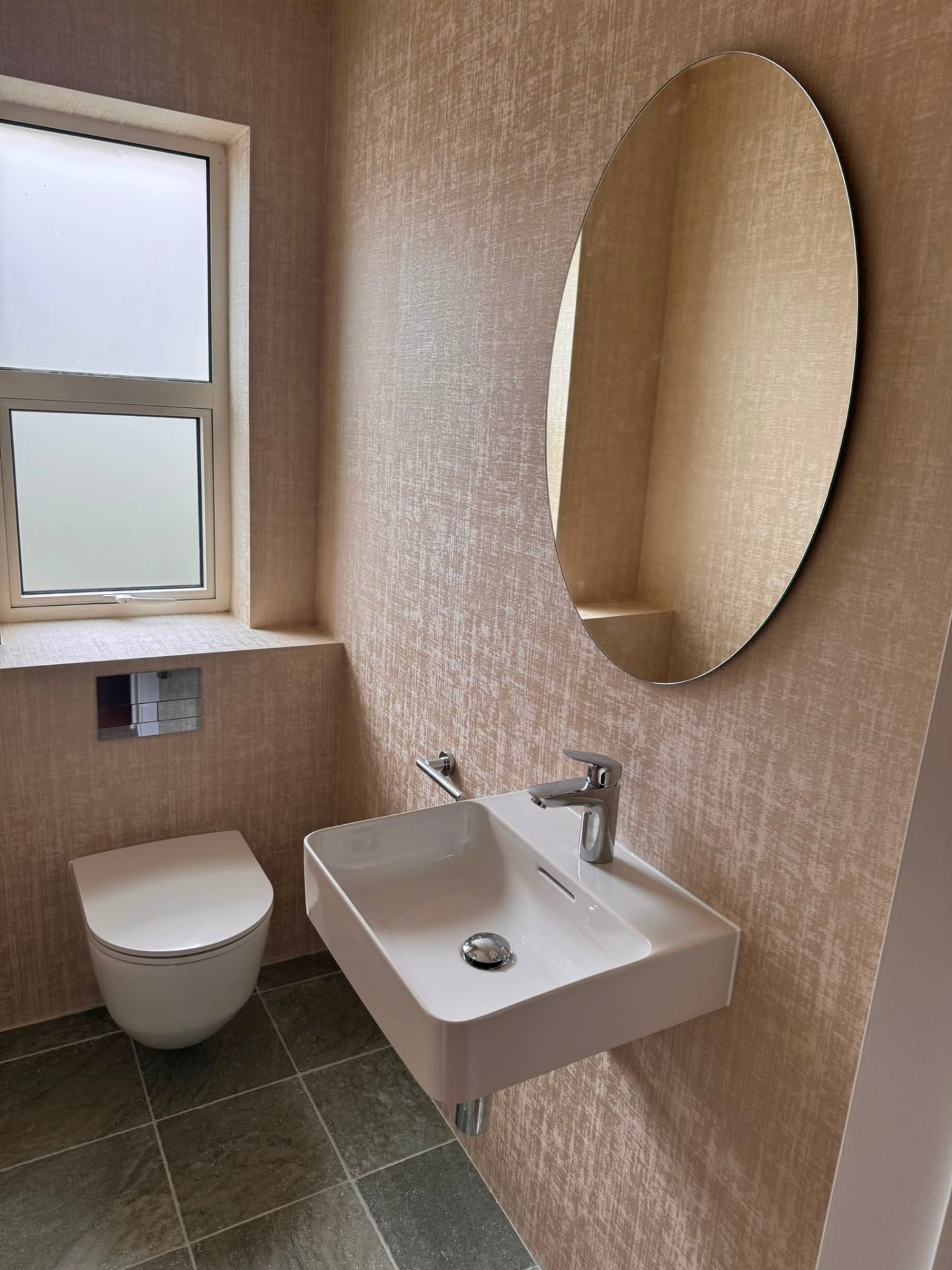 Cloakroom bathroom installation with wall-hung WC, sink and backlit round mirror in Surrey