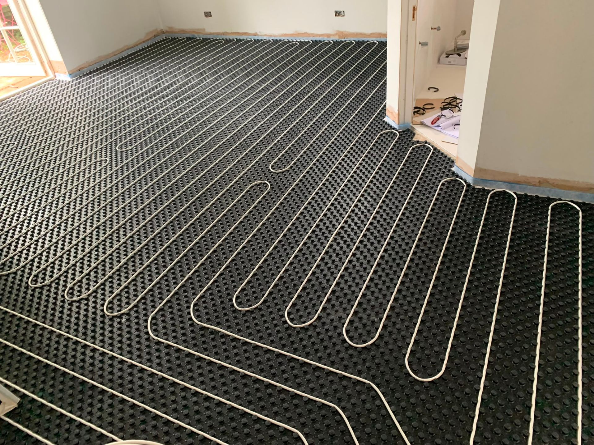 Wet underfloor heating pipe loops laid across a room ready for screed in Surrey