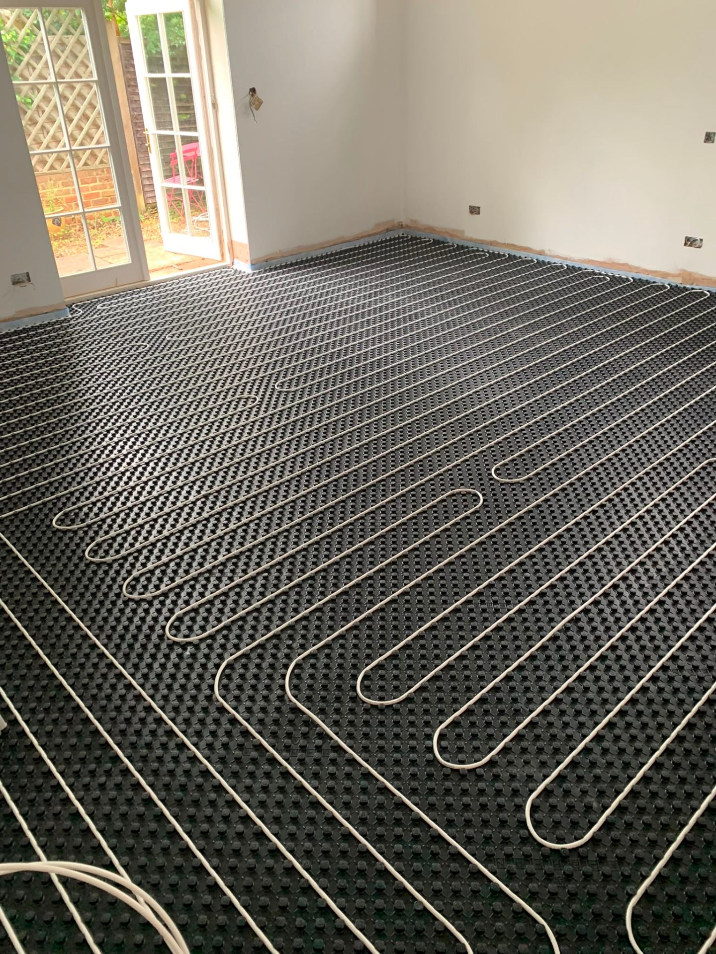 Wet underfloor heating pipe loops laid on insulated panels in a Surrey kitchen extension
