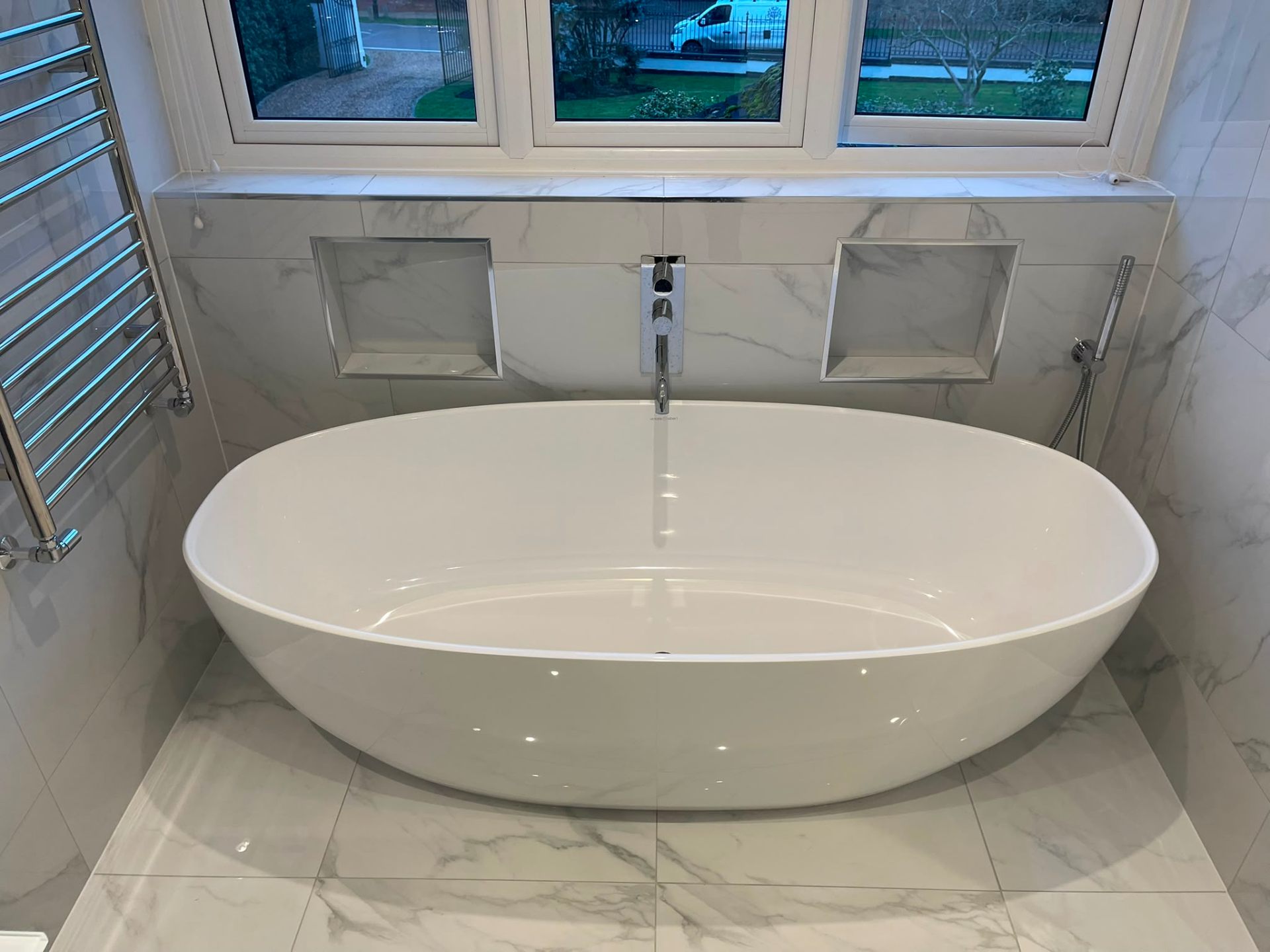Freestanding bath installation with pressurised hot water supply in a marble bathroom, Surrey