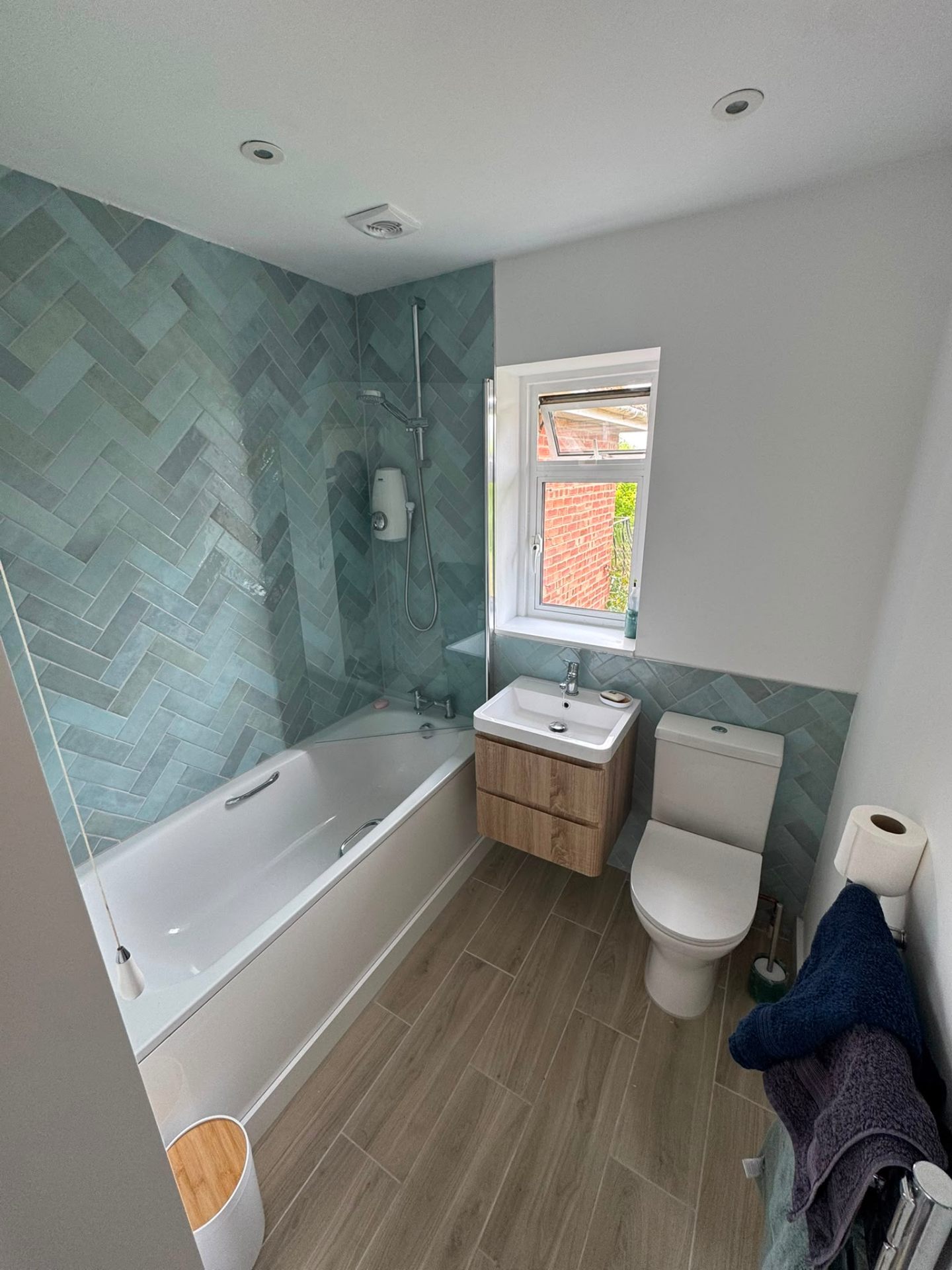 Herringbone-tiled bathroom installation with bath, WC and vanity unit in Surrey